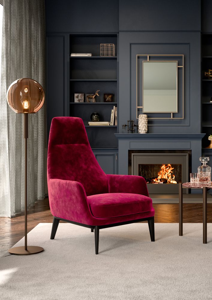 Wohnzimmerszene mit hochlehnbarem Sessel in dunklem Pink, vor einem Kamin mit brennendem Feuer, umgeben von dunkelblauen Einbauregalen und wohnlichen Accessoires.